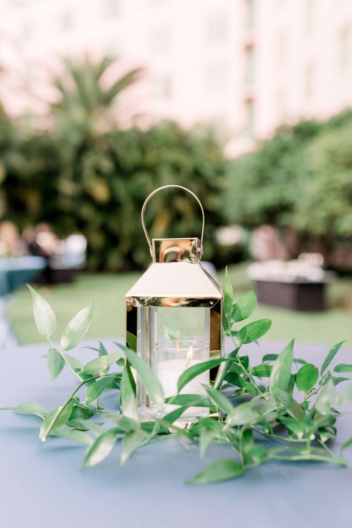 Shiny gold lantern with simple greenery on blue linens