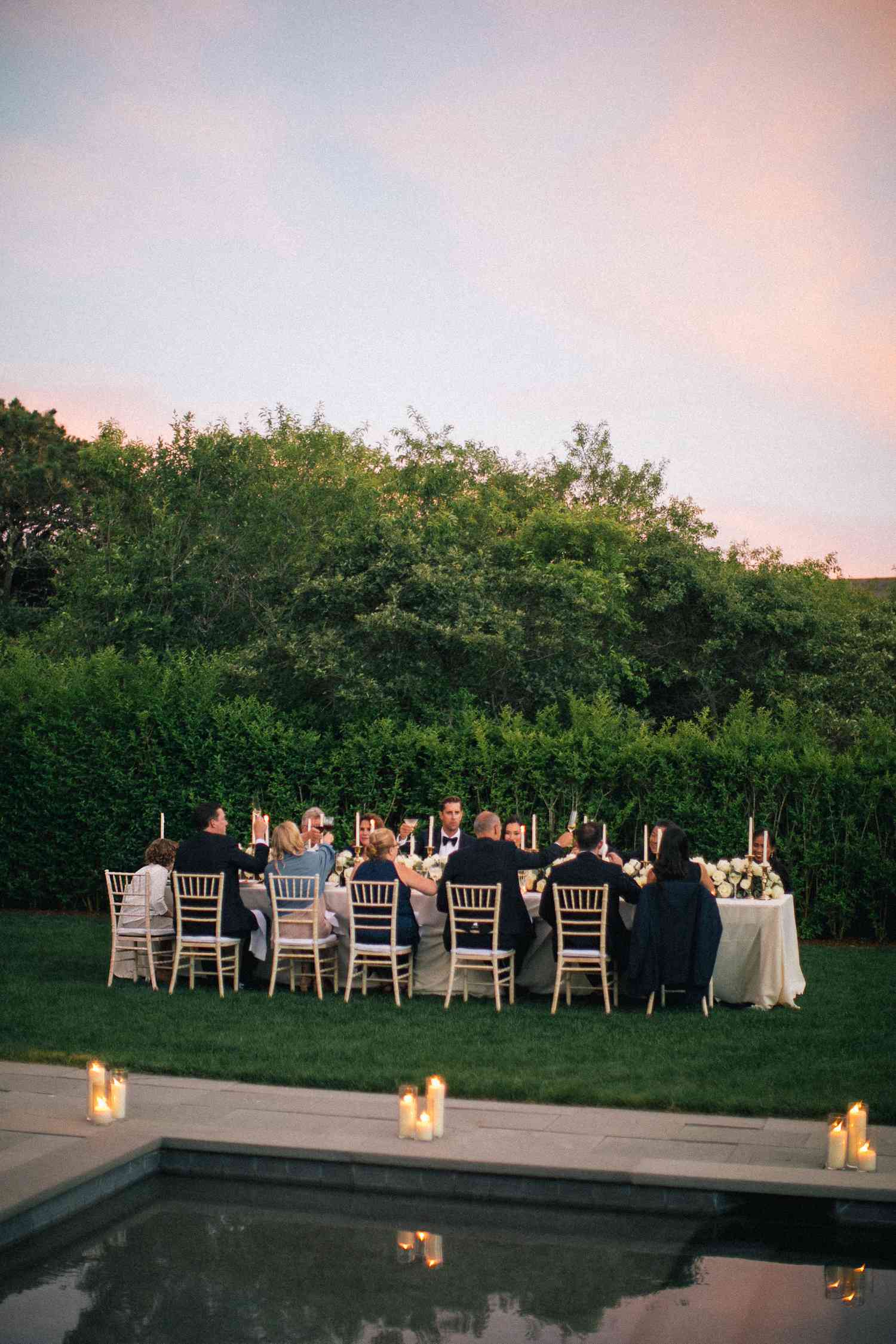 Sunset wedding reception dinner on lush lawn