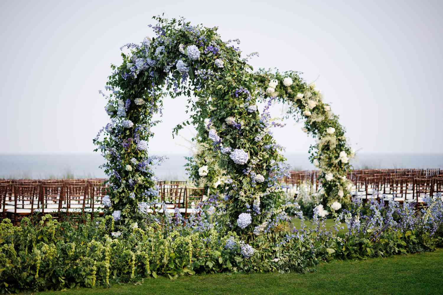 Blue and white floral and greenery arches leading into wedding ceremony
