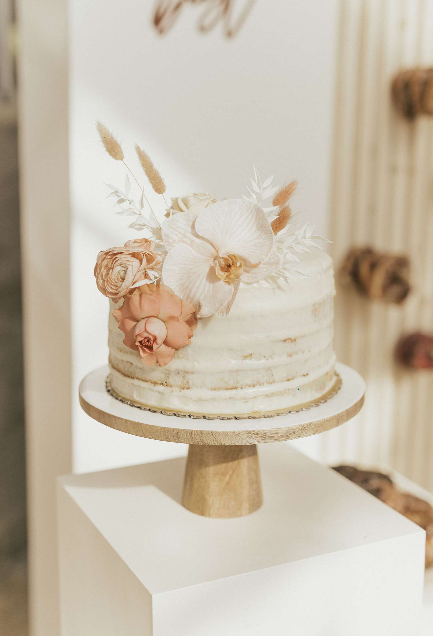 Single tiered wedding cake with boho pink and white flowers and dried foliage