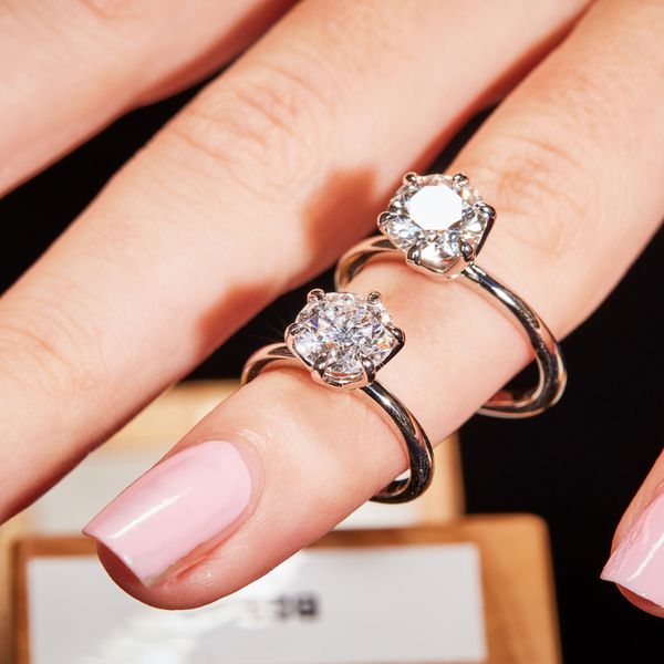 Finger wearing two lab-grown diamond solitaire rings