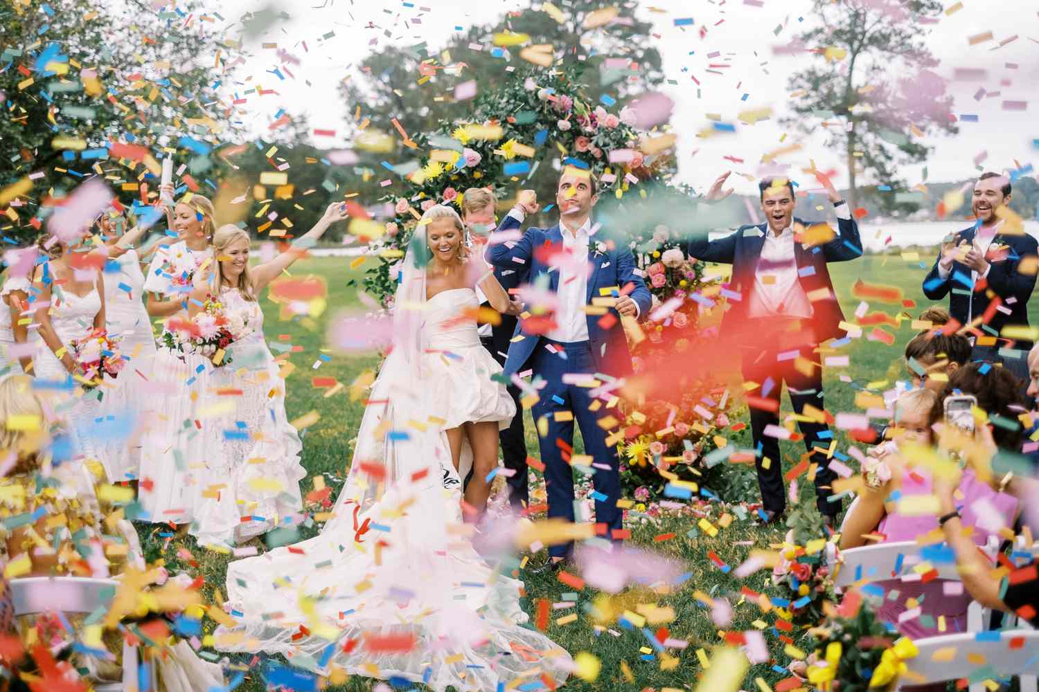 Bride and groom starting their recessional while a canon launches colorful confetti