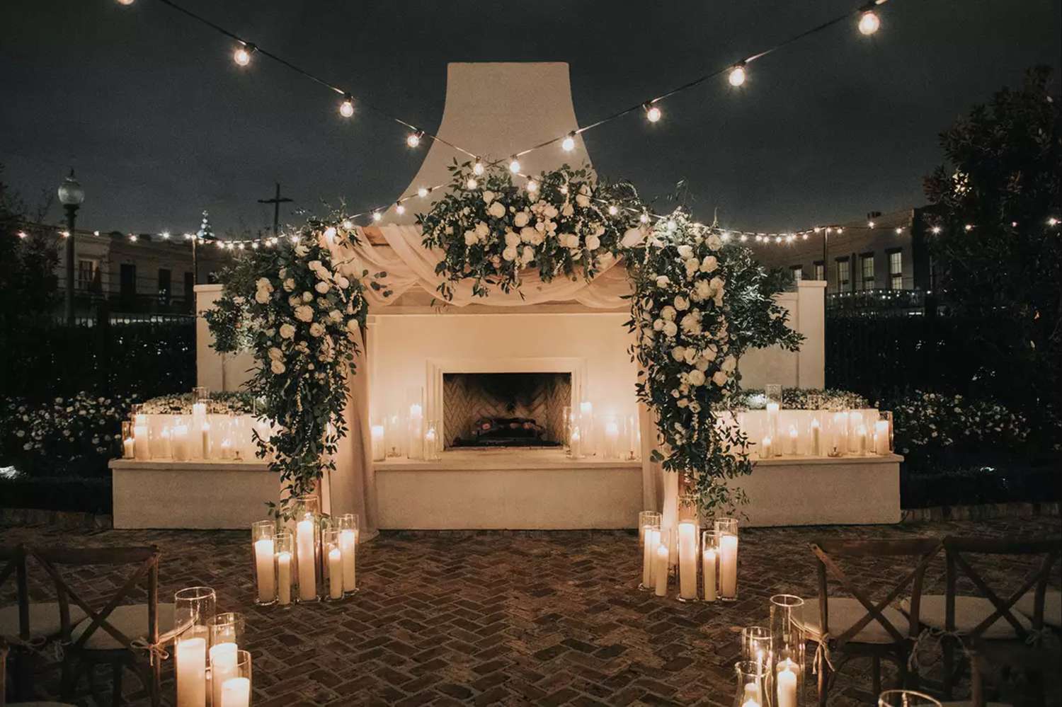 Ceremony space with string lights, floral arch, and pillar candles