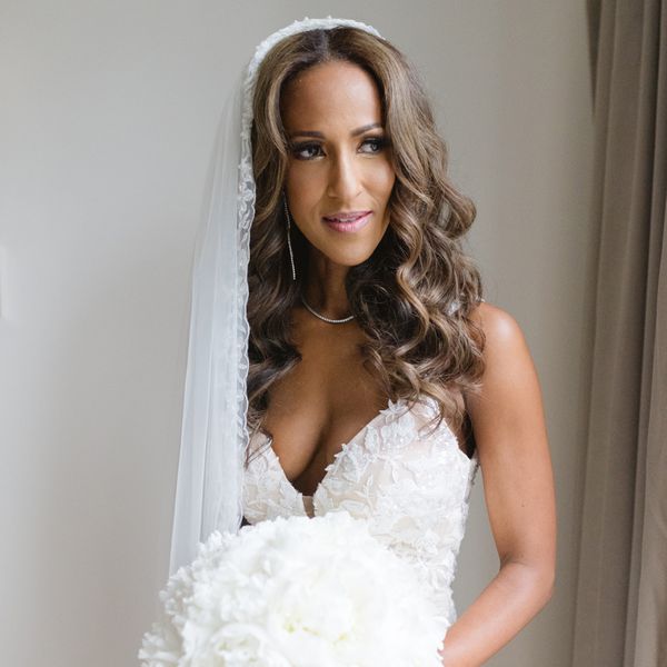 bride with curly light brown hair posing in a veil while wearing a white bouquet