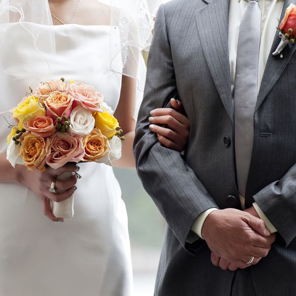 Closeup of Bride Holding Colorful Bouquet and Groomâs Arm