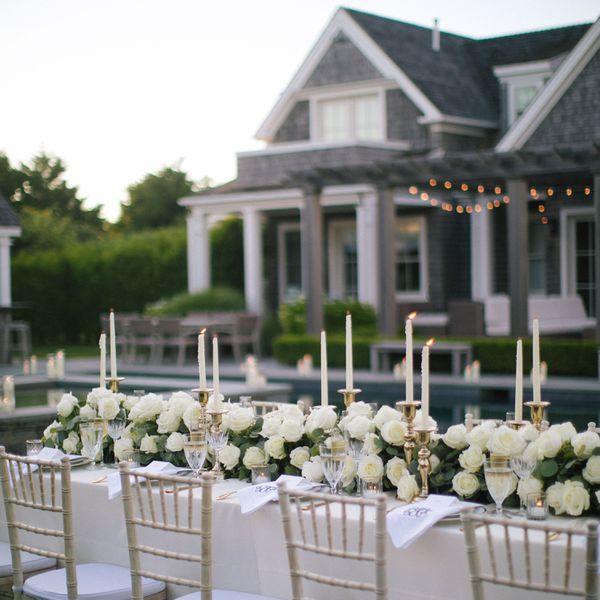 A white rose floral runner centerpiece at a coastal wedding.