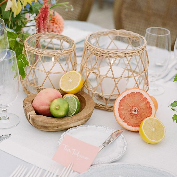 tablescape with citrusâgrapefruit, lemons, limes, and a peachâand white candles in a wicker-like vase
