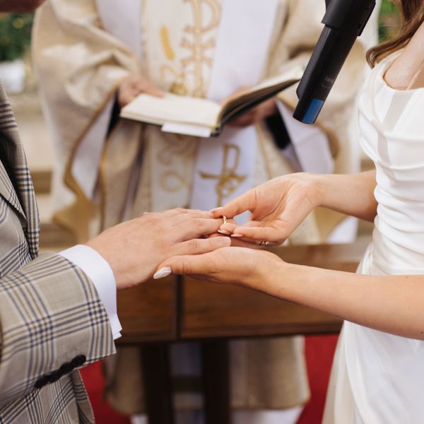 Bride and Groom Exchange Rings in Front of an Officiant While Saying Marriage Vows