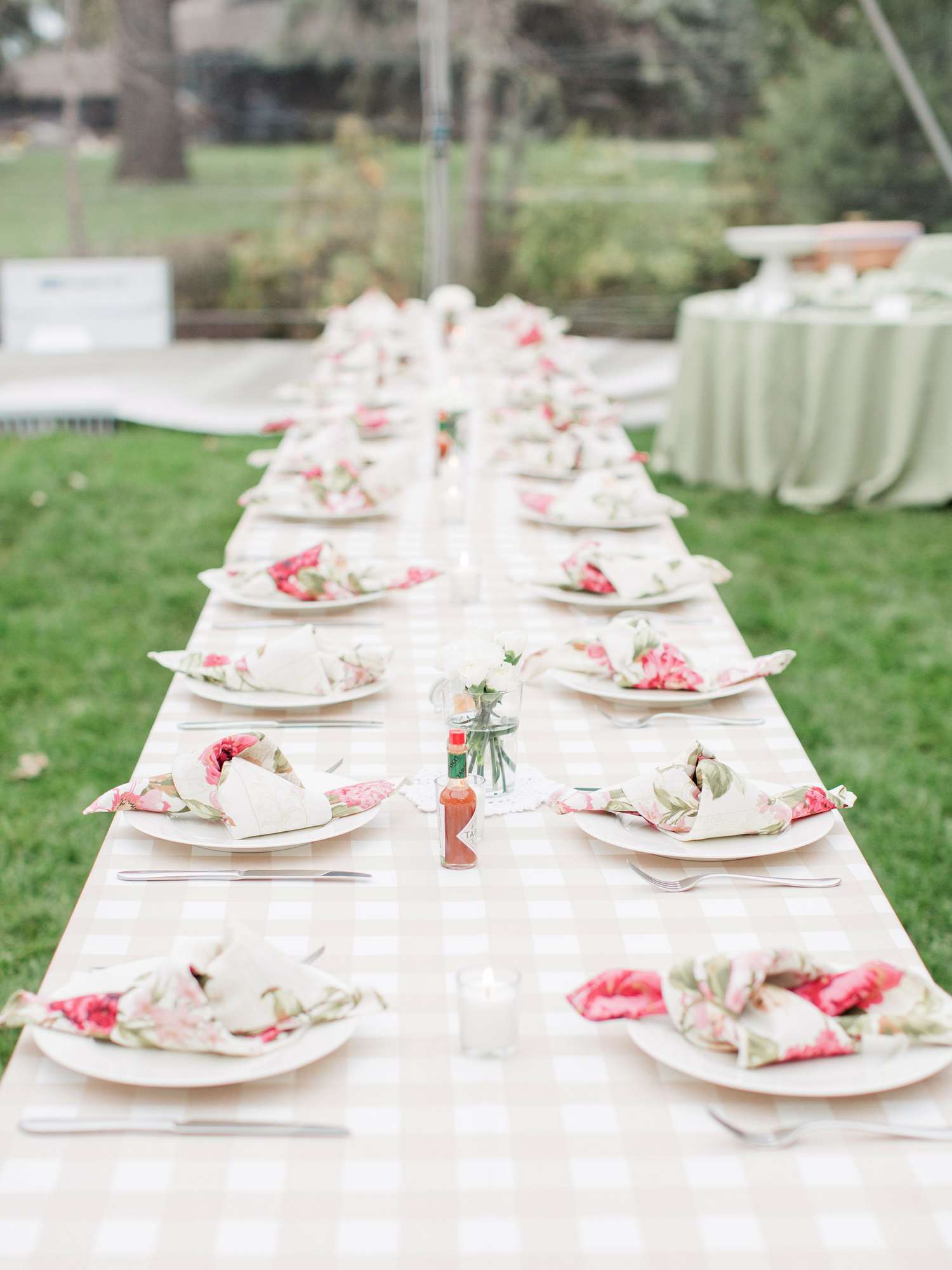 Long Banquet Table With Checkered Linens and Floral Napkins