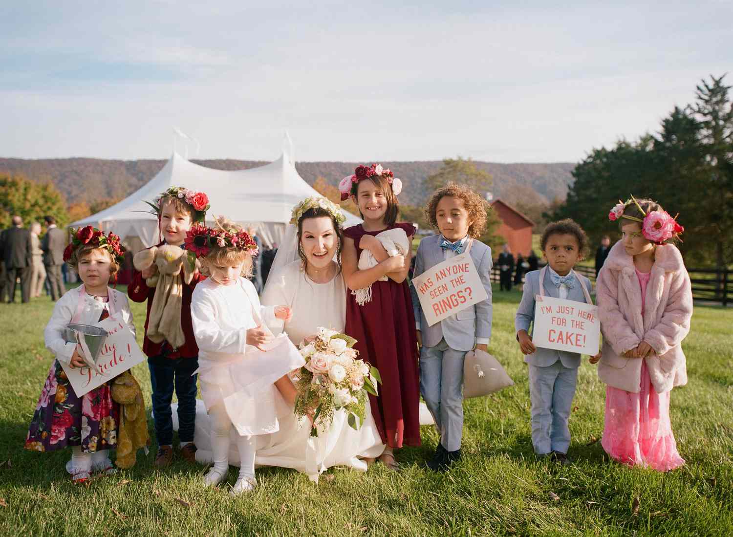 bride with flower girls and ring bearers wearing flower crowns and silly signs