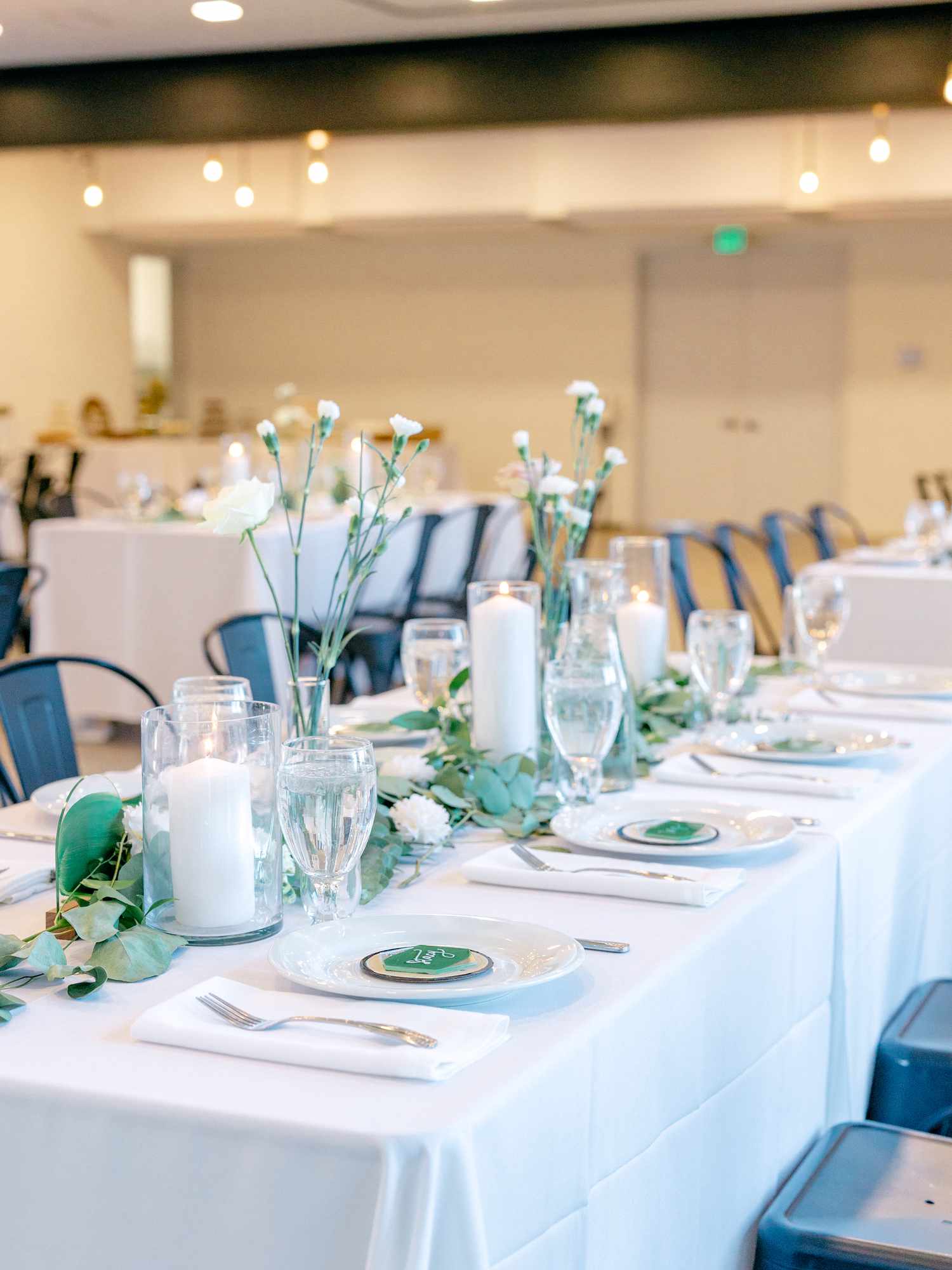 Melissa and Alayna's tables with greenery runner, pillar candles, and record place settings