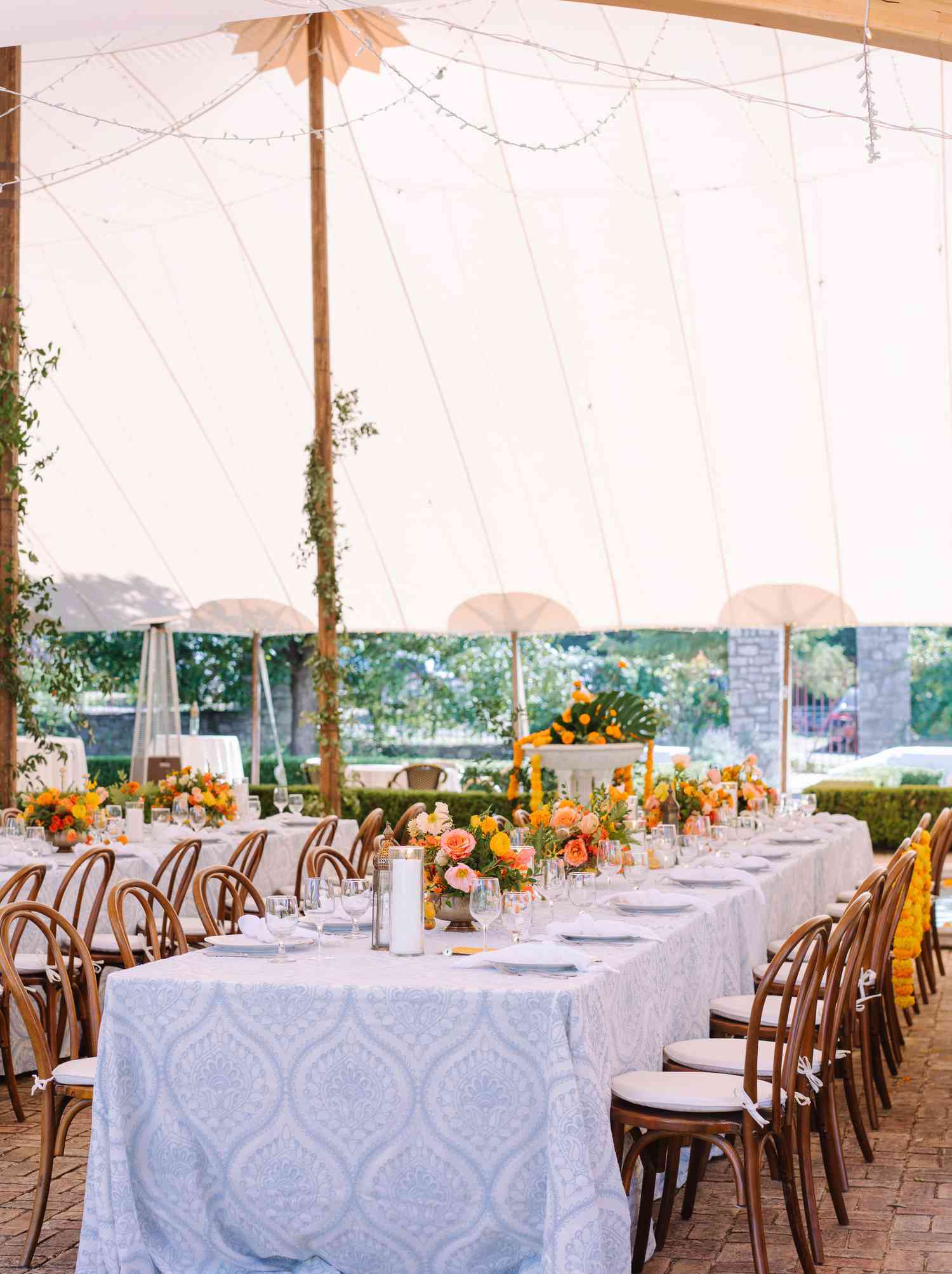 Meredith and Eshaan's tables with a blue and white patterned tablecloth and bright floral centerpieces
