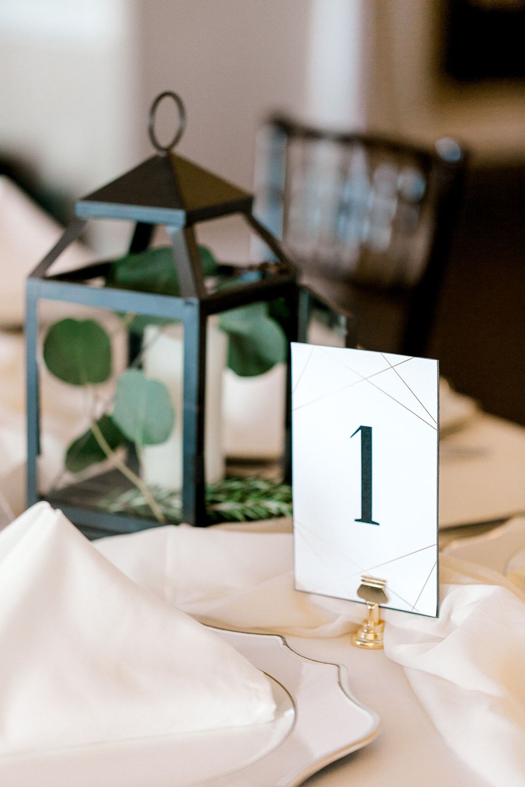 black lantern with greenery and modern table number sign