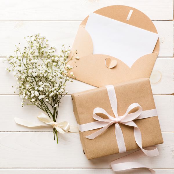 Wedding mockup with white paper list and flowers gypsophila on colored table top view flat lay