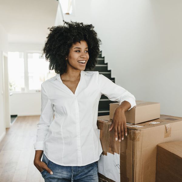 Woman in White Shirt Standing Next to Moving Boxes in Empty House