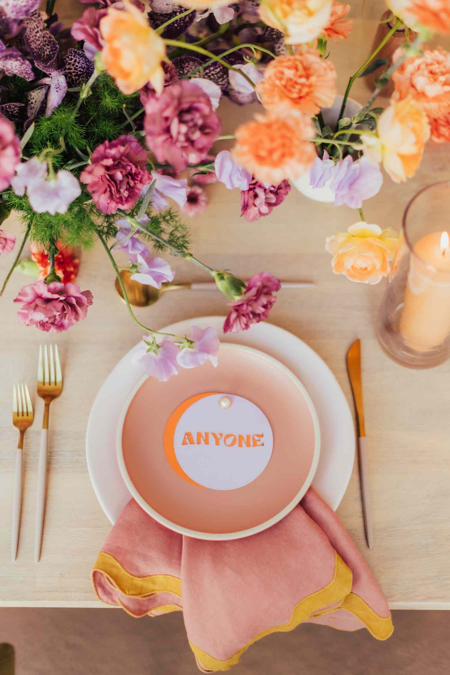 Place setting with white charger, peach plate, "anyone" place card, and peach and yellow scalloped napkin
