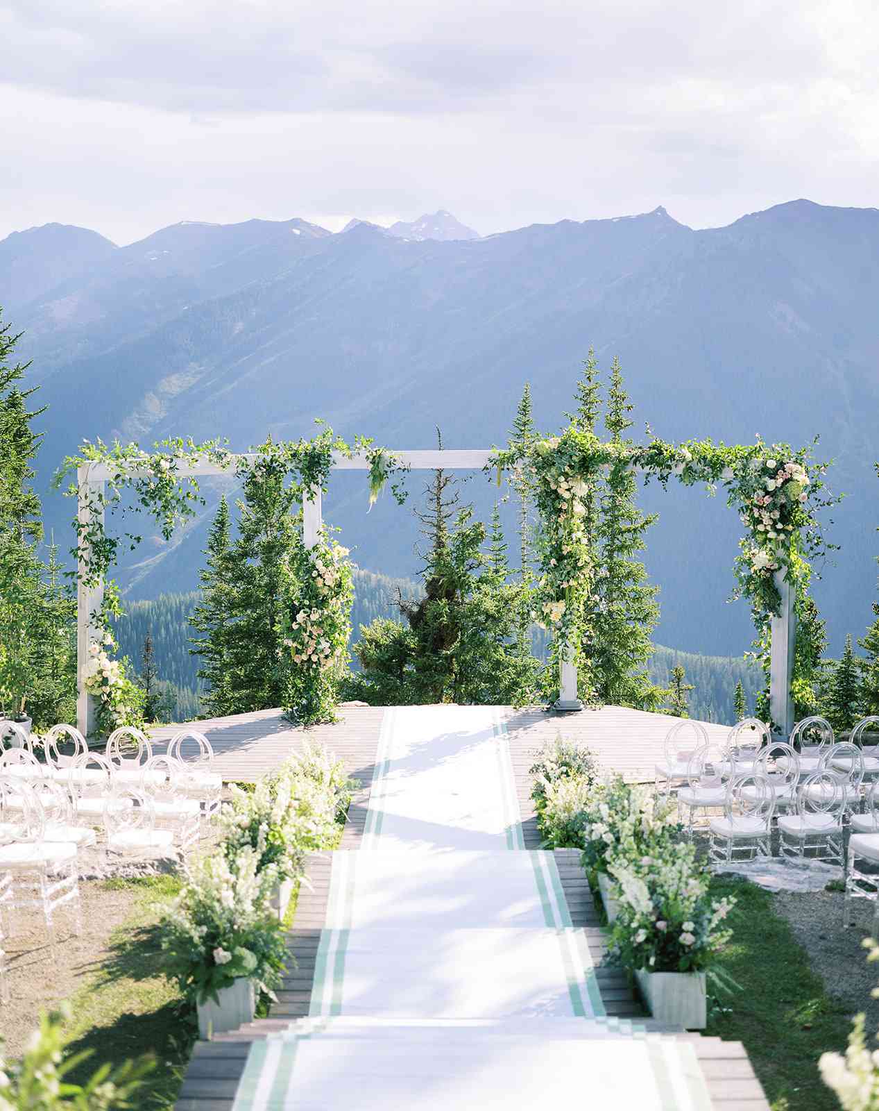 massive mandap decorated with greenery positioned in front of a mountainous backdrop