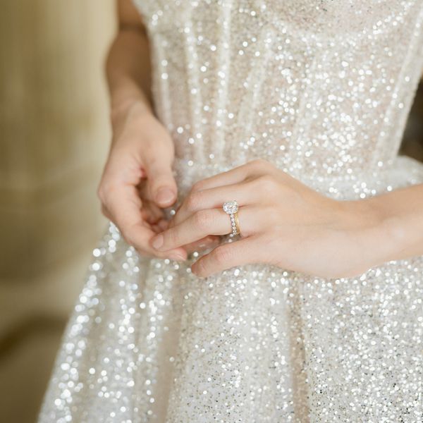 close up shot of a bride's hands in front of a fully sequined wedding dress