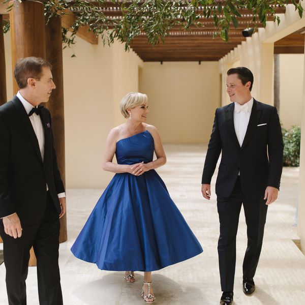 A woman in a blue strapless gown and two men in tuxedos