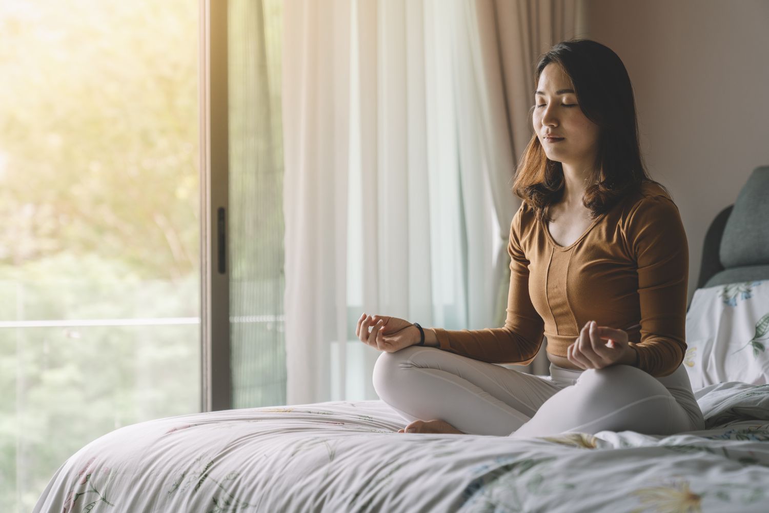 Woman sitting on bed meditating