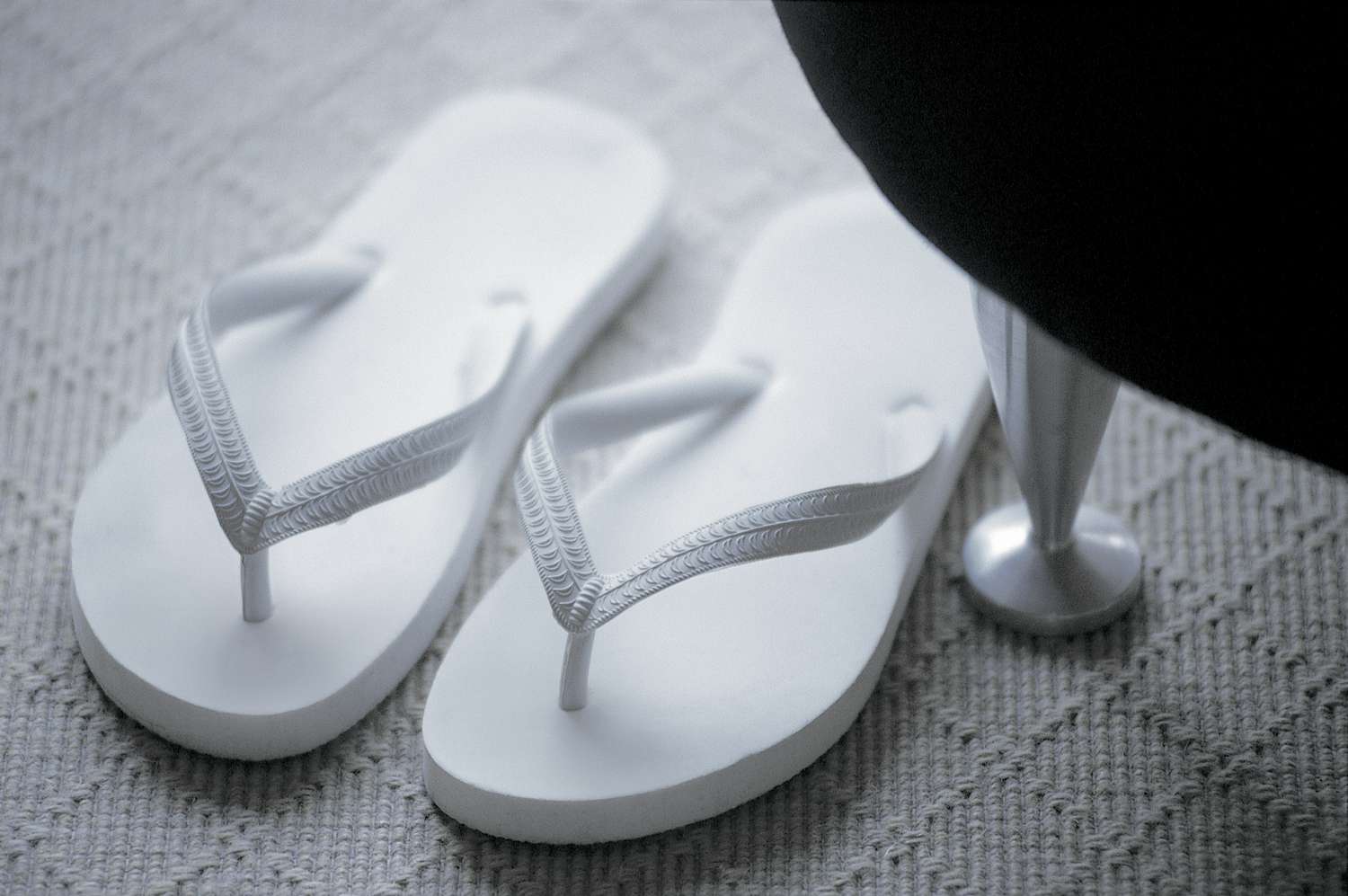 Pair of white flip-flops on the carpet at home