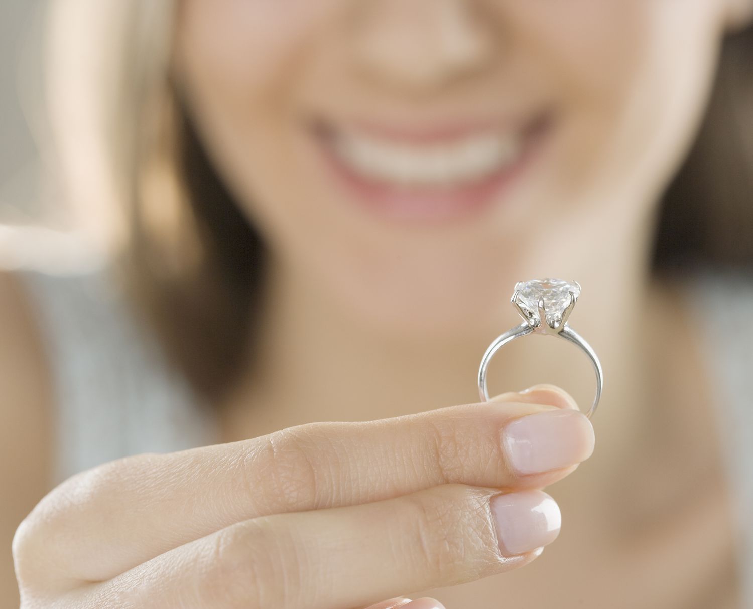 Woman holding solitaire diamond engagement ring