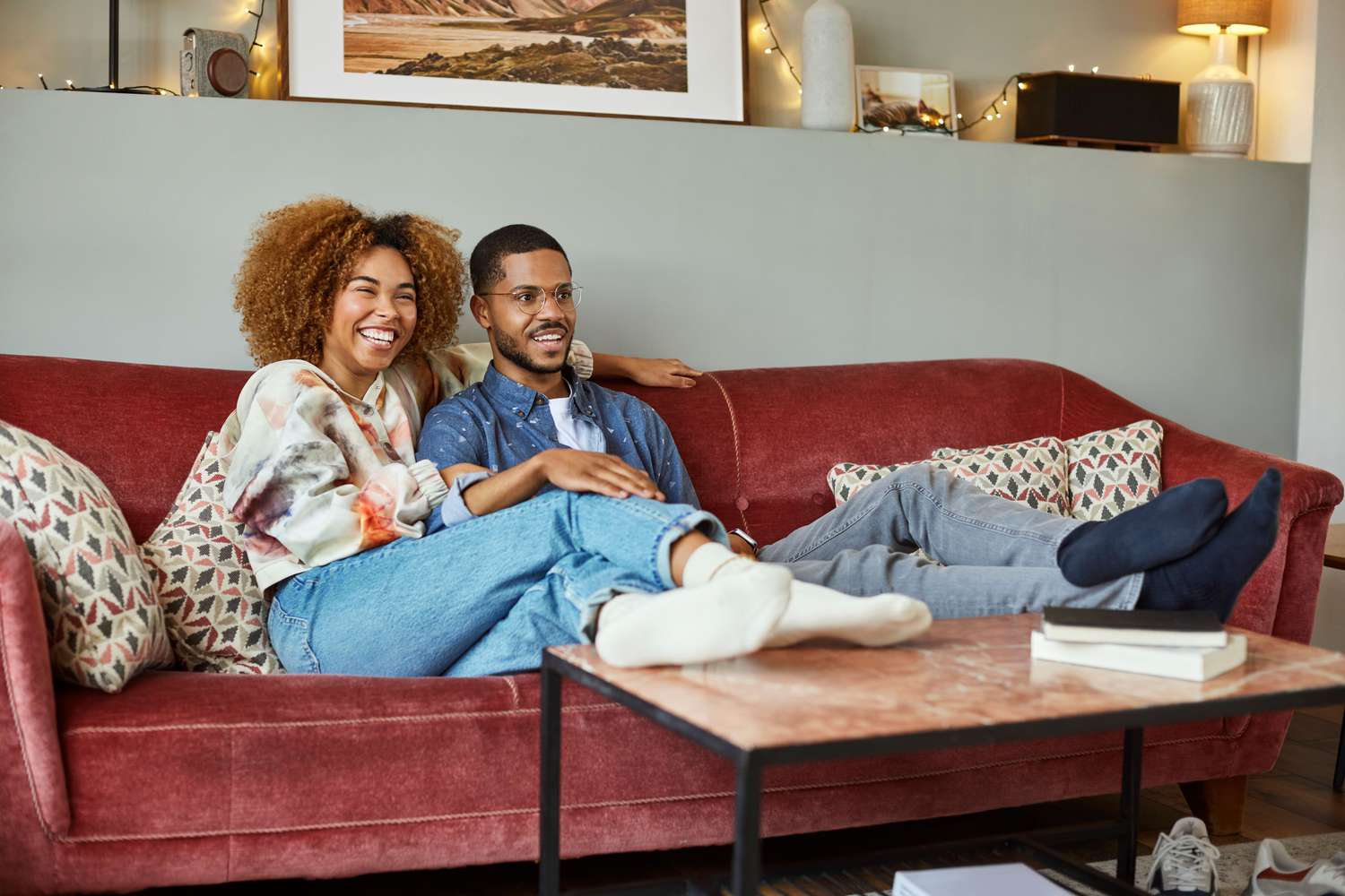 Couple watching TV on the sofa at home and laughing