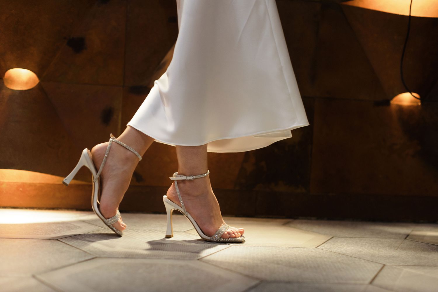 Woman walking in white heels with sequined straps