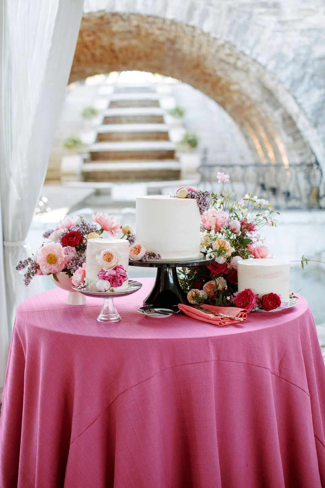 trio of wedding cakes with flowers on magenta table linen