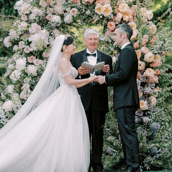 bride and groom holding hands at the altar while a wedding officiant reads from a book
