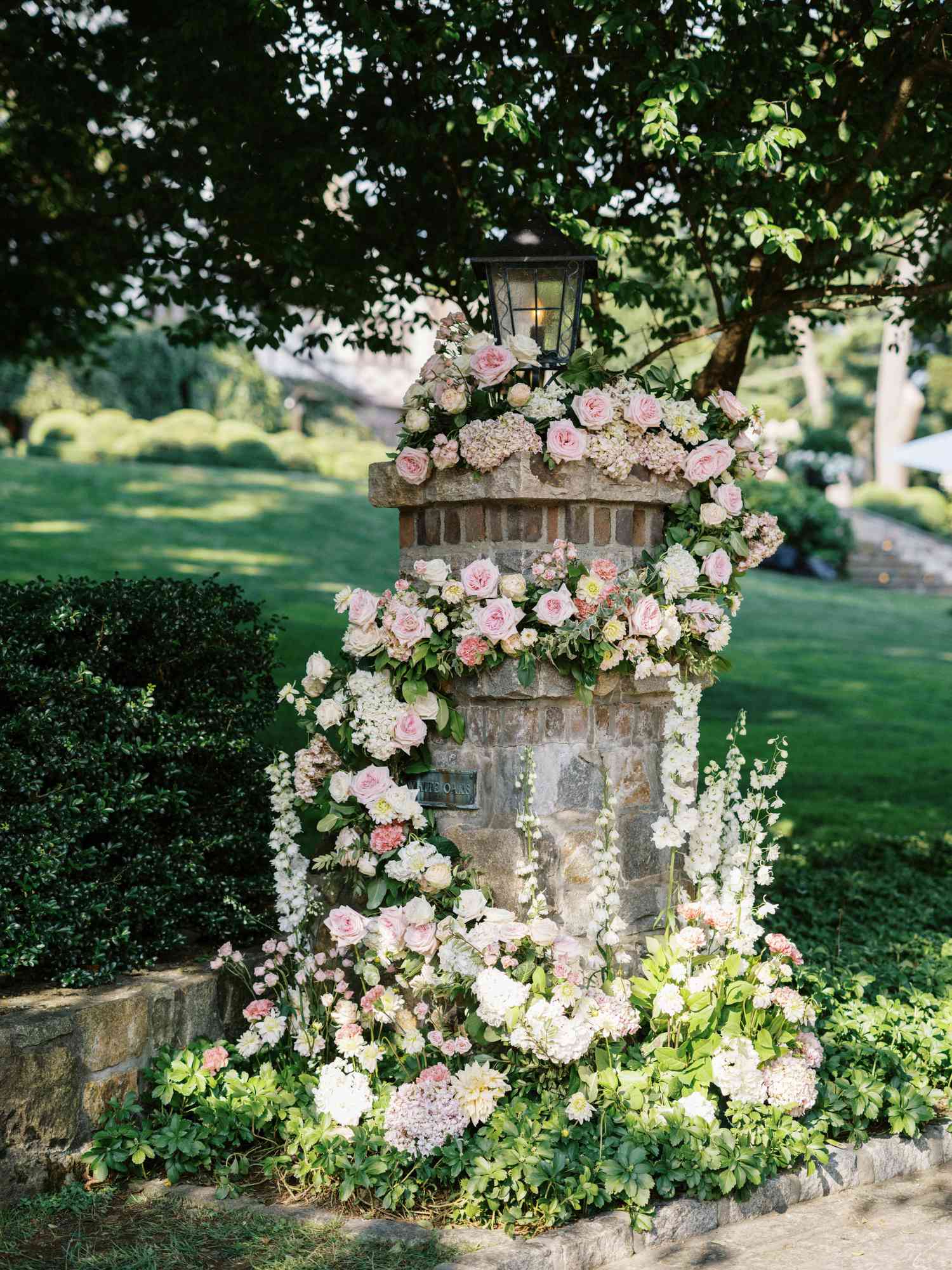 Stone Pillar at At-Home Wedding Entryway Covered in Roses, Dahlias, Snapdragon, and Greenery