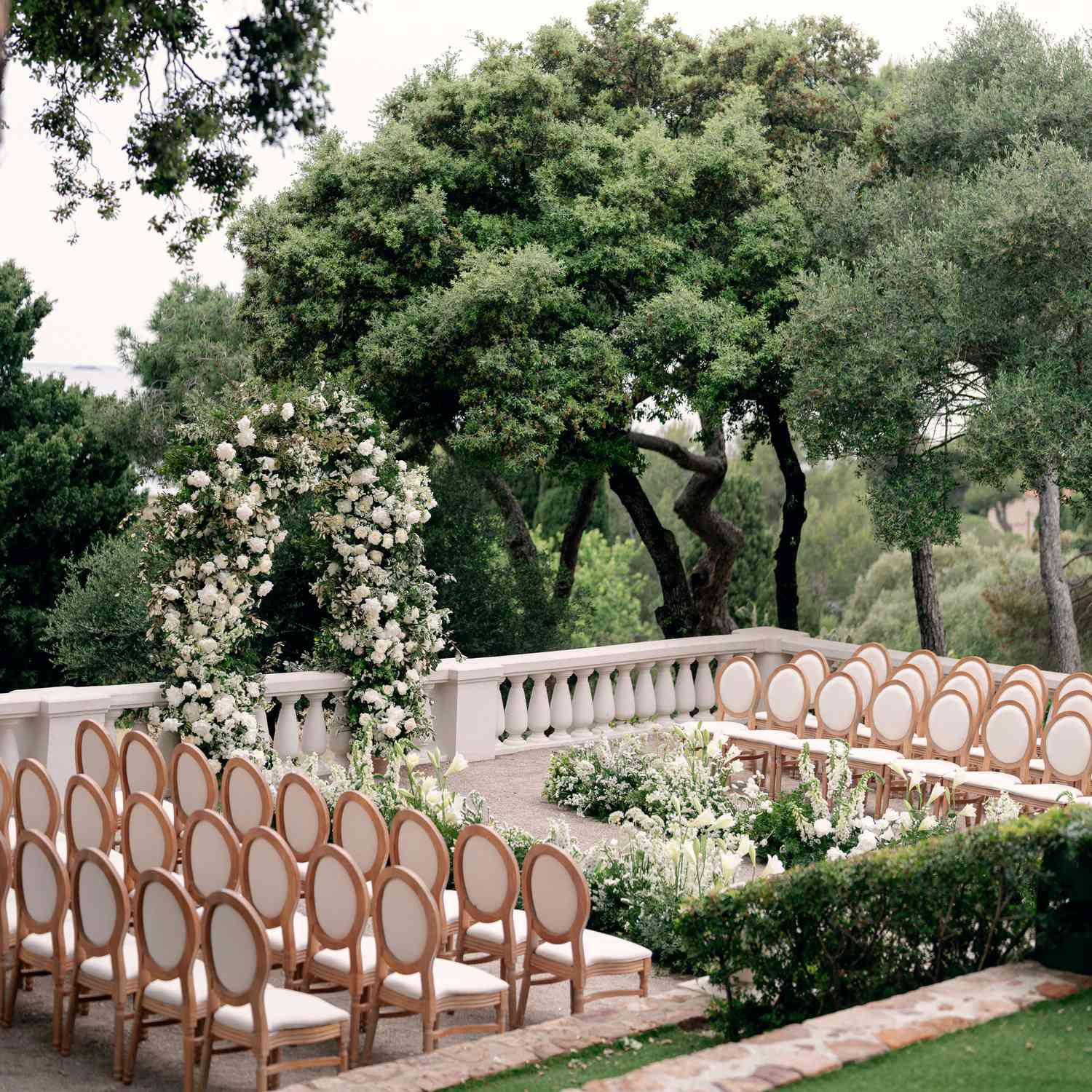 Outdoor Wedding Ceremony With White and Green Floral Ceremony Structure