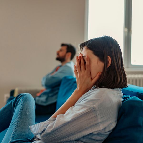 Woman Puts Her Head in Her Hands as Her Partner Displays Passive-Aggressive Behavior in Their Relationship