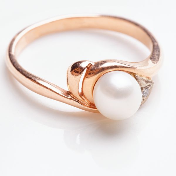 Gold wedding band with a pearl center stone and diamonds next to the gem