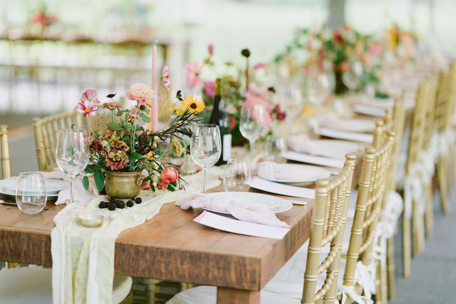 gauzy table runner with florals and fruit on wood table with gold chairs