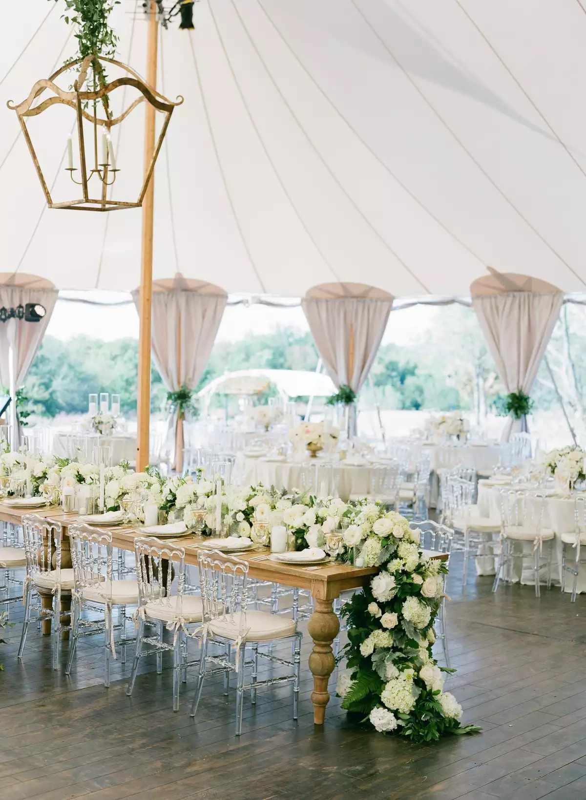 lush white and green floral centerpiece in tented reception area