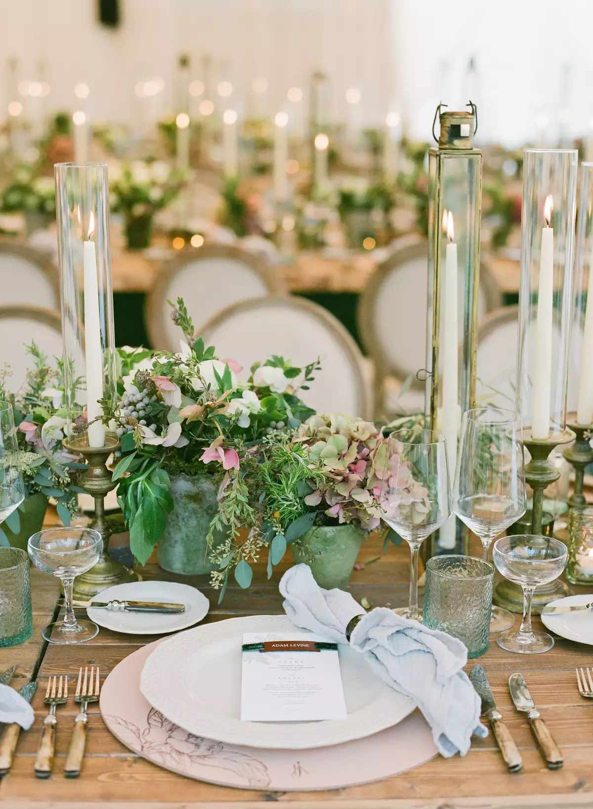 tall skinny lanterns interspersed with taper candles and green and pink florals