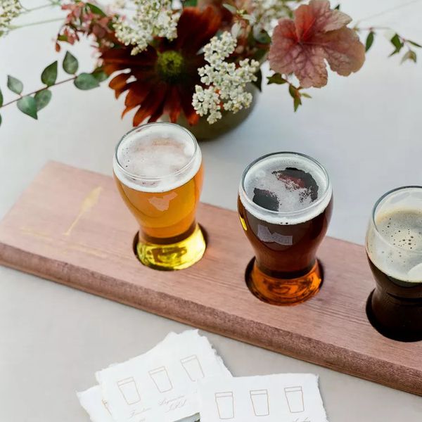A beer flight on a white table with pink and white flowers at a brewery wedding venue.