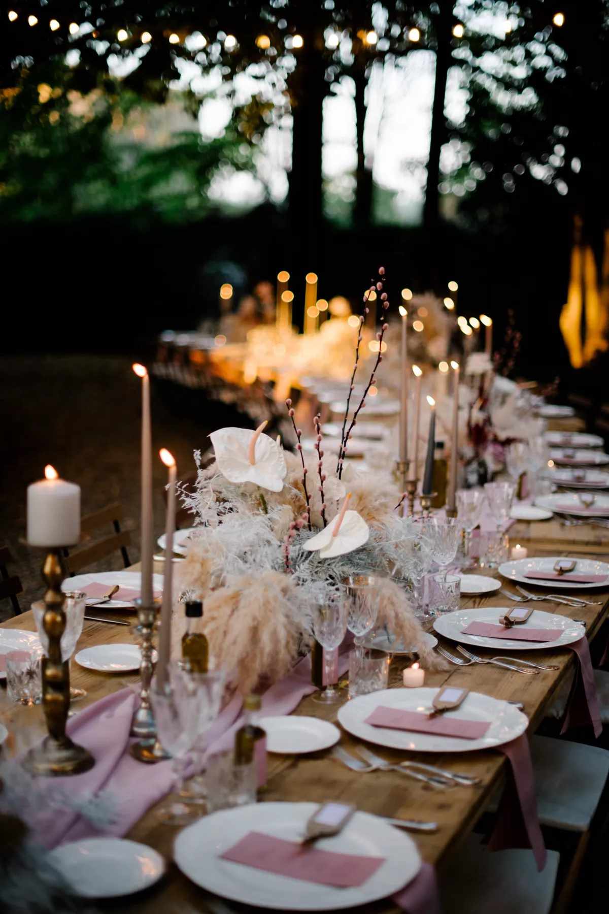 pink linen table runner with orchids, feathers, and lit candles