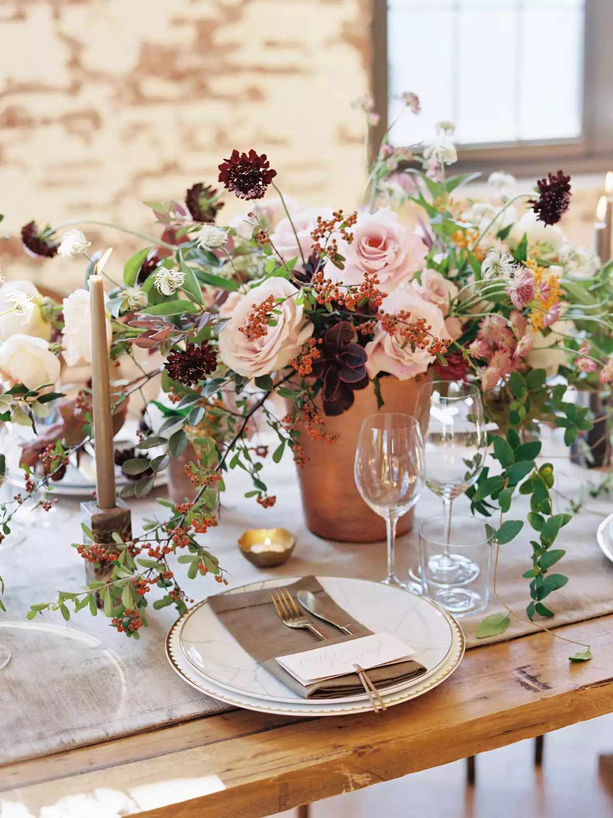organic floral centerpiece of pink and brooding crimson blooms on linen table runner