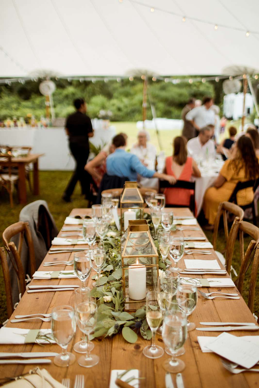 gold lanterns with greenery on wood table with wood chairs