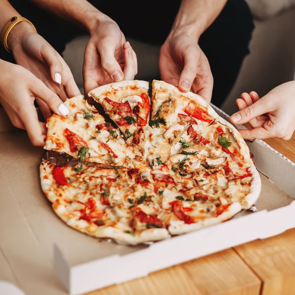 Hands of young people taking pizza slices from delivery box dining together,