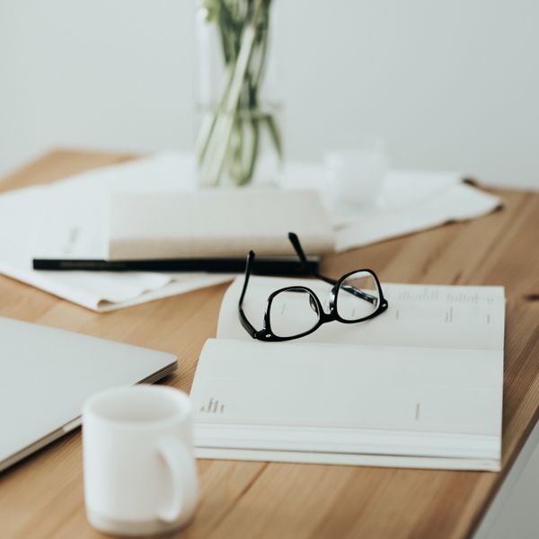 Workspace table with laptop, eyeglasses, schedule calendar and coffee