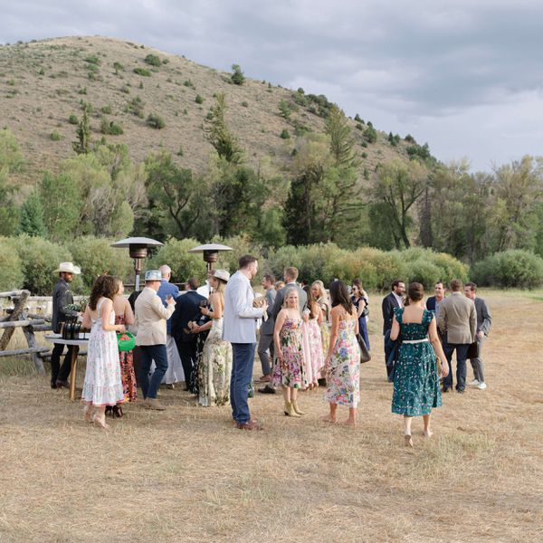 wedding guest standing in an open field with a mountainous backdrop