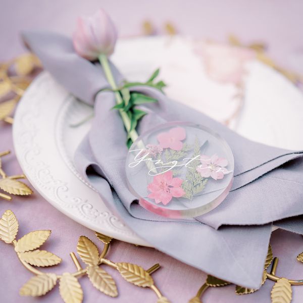 Round Lucite Place Cards With Pink Pressed Flowers and Ferns on Lavender Napkin, Engraved Plate, and Gold Leaf Charger