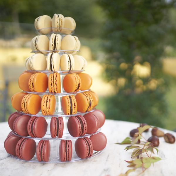 A wedding cake of pink macarons, orange macarons, and white macarons.
