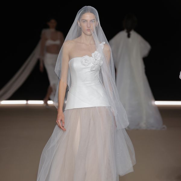model wearing a one-shoulder wedding dress with a tulle skirt and blusher veil