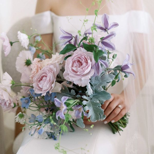 Bride holding a purple bouquet of garden roses and clematis