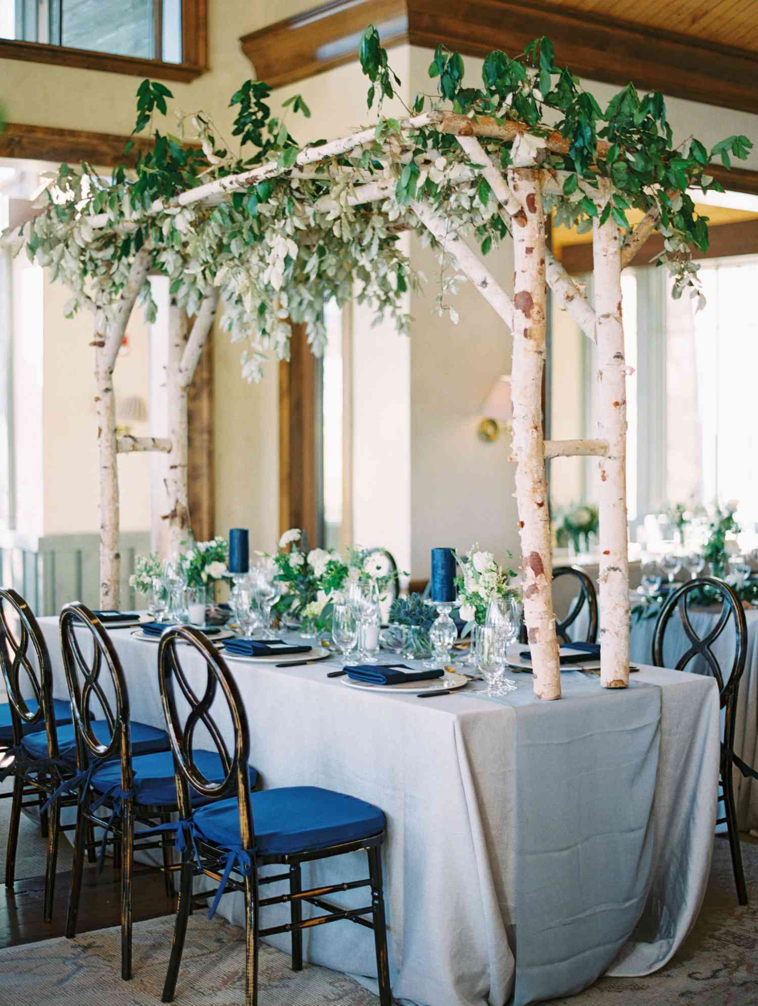 Blue wedding reception with wooden canopy and greenery