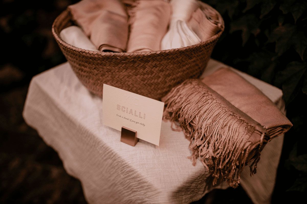 Wicker basket of pink and rose-colored blankets at backyard wedding